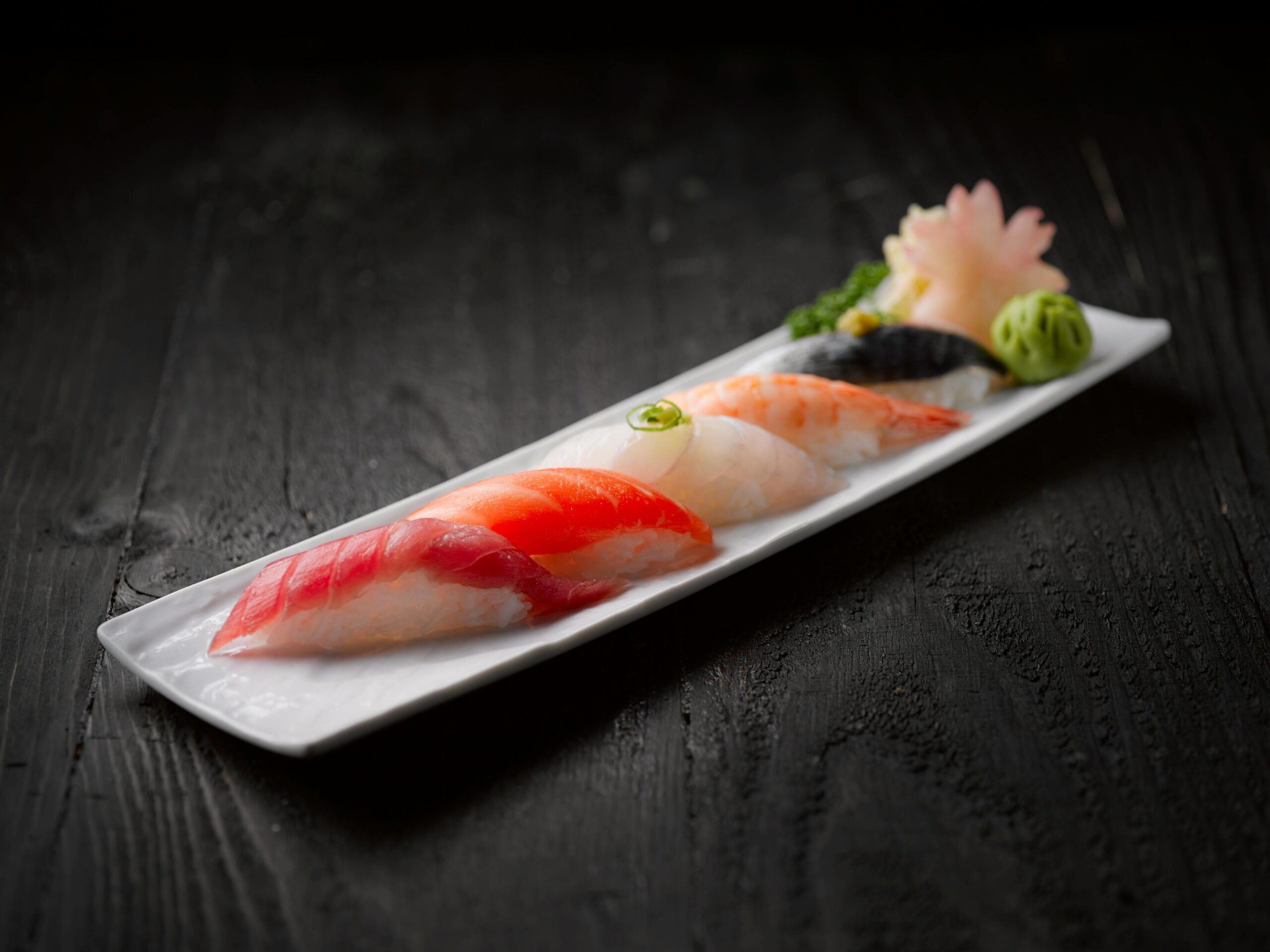 Elegant sushi platter featuring assorted seafood sushi on dark wood table.